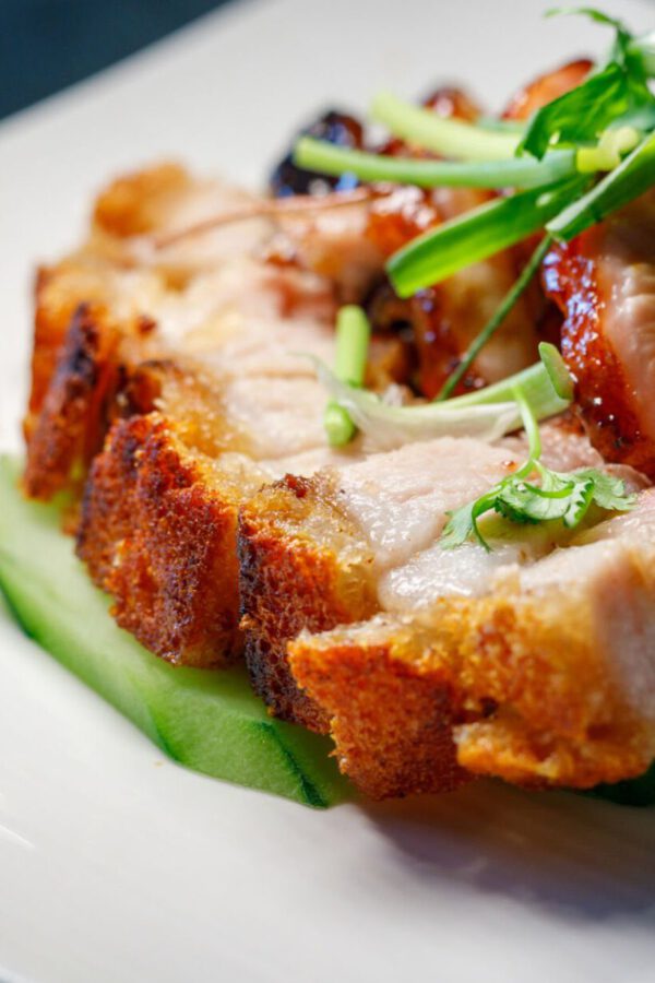 Schweinekrustenbraten schön angerichtet mit Garnitur auf weißen Teller