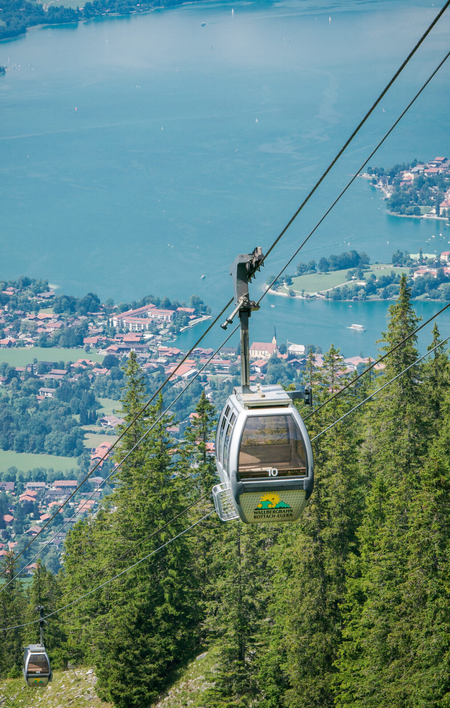 Gondel fährt Berg hinauf, Tegernsee im Tal