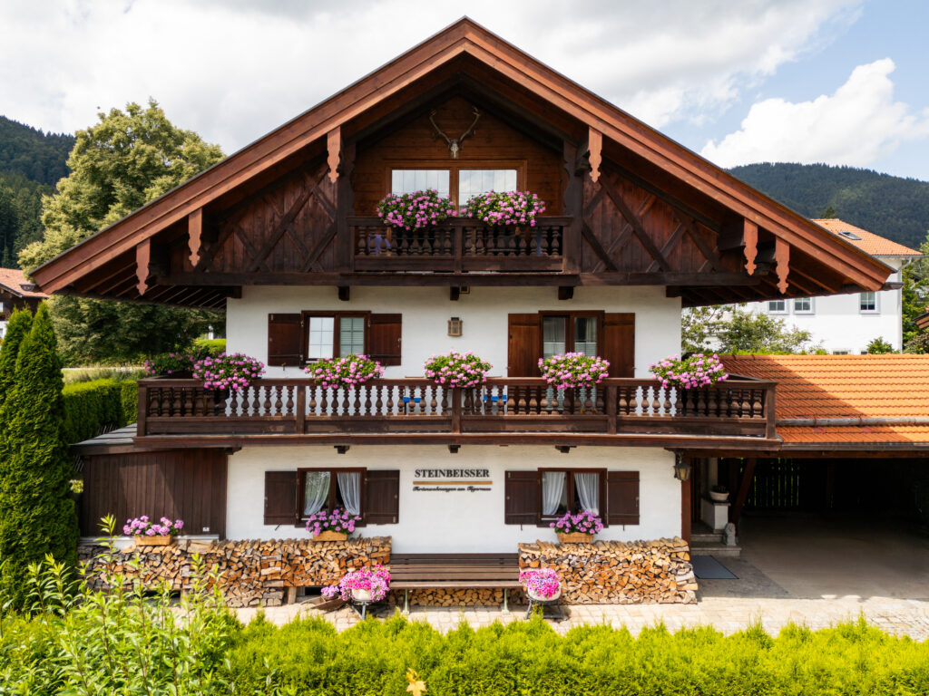 Frontale Hausansicht Ferienhaus am Tegernsee, bepflanzte Blumentöpfe, traditionelles bayerisches Haus mit Holzvertäfelung