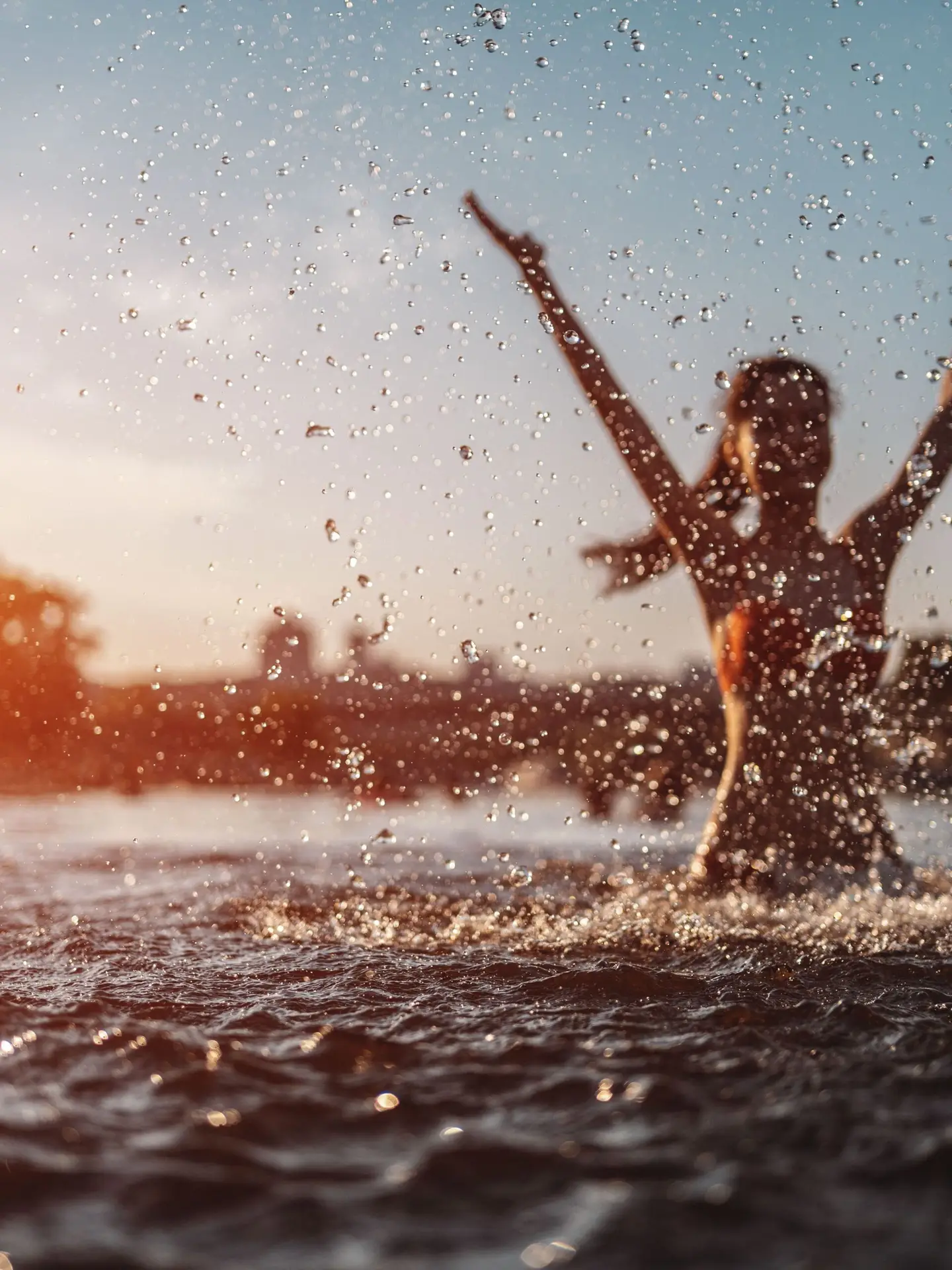 happy female in red bikini splashing or play in water and have fun at sunset